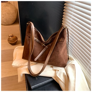 Detail of dark brown suede tote bag with slim shoulder straps and gold hardware accents