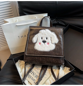 Detail of coffee brown PU leather backpack with a plush puppy patch in a luxury setting