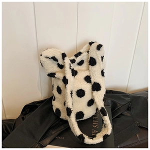 Detail of plush polka dot bucket bag showing soft shearling texture and black dots