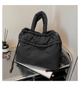Detail of black quilted puffer tote with drawstring closure on a metallic trolley