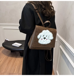 Detail of vintage dark brown backpack with a cute white bichon frise dog embroidery