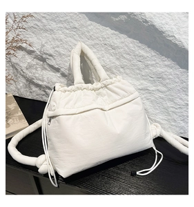 Detail of white quilted tote bag featuring a side drawstring and hidden zipper pocket