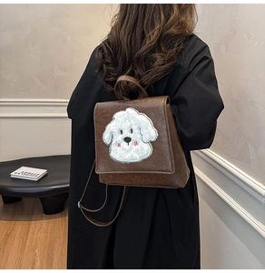 Detail view of vintage brown leather backpack with cute white plush dog embroidery motif