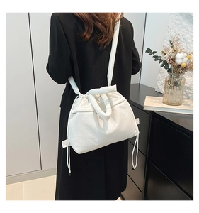 Rear view of a model wearing a soft white quilted puffer bag with drawstring details