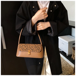 Close-up of leopard print flap and gold metal buckle on a retro brown shoulder bag