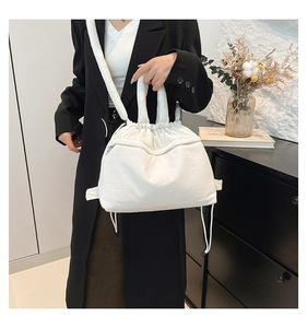 Macro shot of white quilted puffy tote bag featuring side zipper and adjustable strap