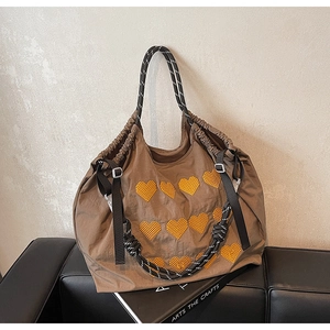 Detail of brown nylon tote with yellow hearts and woven rope handles on art books