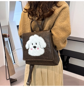 Detail of vintage brown leather backpack with cute bichon puppy embroidery on model