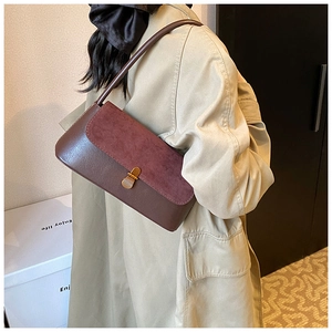 Detail of vintage dual-material underarm bag with bronze buckle and wine red suede flap