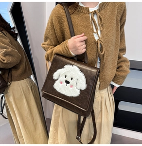 Detail of dark brown leather backpack featuring a cute plush dog patch on a stylish model