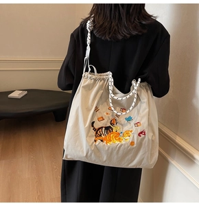 Detail der süßen Katzenstickerei und der gewebten Seilgriffe an einer beigen Stofftasche