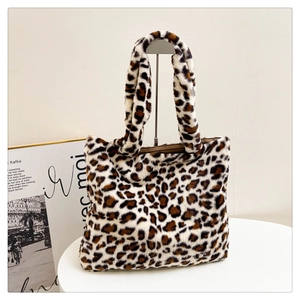 Dettaglio della borsa tote leopardata in peluche appesa a un supporto con luci soffuse