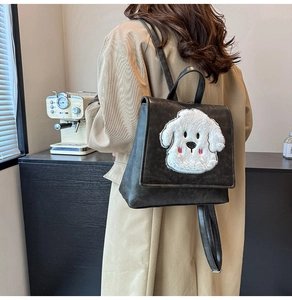 Detail shot of grey faux leather backpack featuring a plush white cartoon dog patch on flap