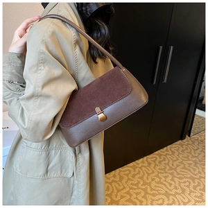 Detail of vintage brown leather underarm bag with suede flap and metal buckle on a model