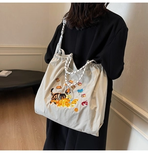 Detail der Katzenstickerei auf einer beigen Canvas-Tasche mit geflochtenen Seilgriffen