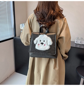 Detail of a vintage retro backpack with a cute white plush puppy embroidery and top handle