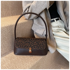 Detail of vintage underarm bag featuring leopard print flap and metal clasp on stone