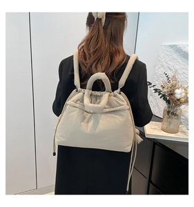 Detail of soft quilted nylon backpack in off-white featuring side drawstring and padded straps