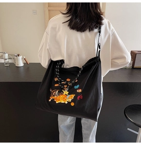 Rückansicht einer schwarzen Canvas-Tasche mit Katzenstickerei und gemustertem Gurt