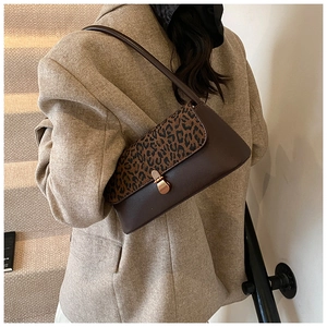 Detailed view of leopard print shoulder bag with gold clasp shown on a beige blazer