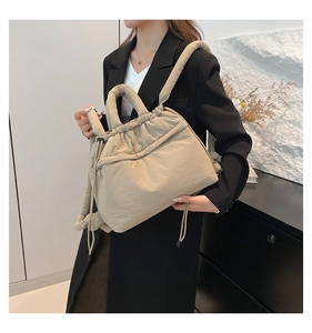 Quilted beige drawstring handbag with zipper pocket shown on a model in modern setting
