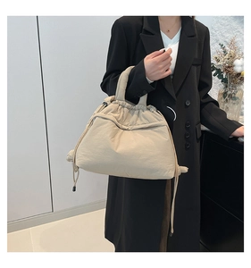 Detail of beige quilted puffer tote bag featuring soft drawstrings and nylon texture