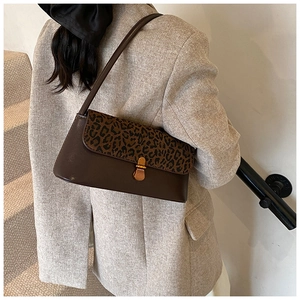 Detail showing vintage leopard print flap and metal buckle on brown shoulder bag