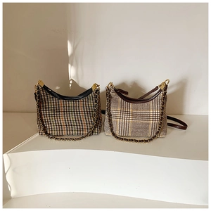 Close-up of houndstooth hobo bag with gold chain strap on minimalist white stairs