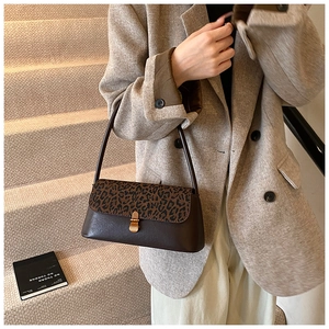 Close-up of leopard print flap and vintage gold clasp on brown leather shoulder bag