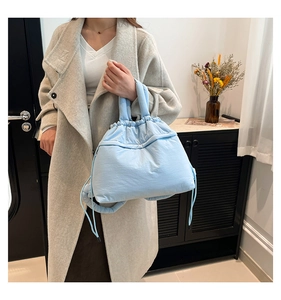 Close-up of a light blue puffy quilted tote bag styled with a grey winter coat