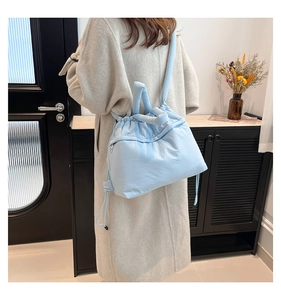 Detail of light blue puffy tote bag with drawstring closure and soft quilted texture