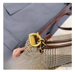 Close-up of golden chain hardware and premium leather trim on a plaid shoulder bag