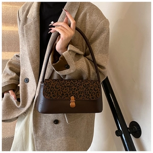 Detail of leopard print flap and gold metal buckle on vintage brown shoulder bag