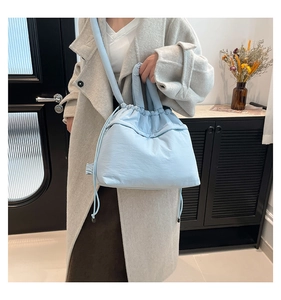 Detailed view of light blue quilted tote bag with drawstring and soft padded texture