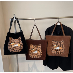 Detailed view of suede tote bags featuring leopard cat patch and cartoon dog embroidery