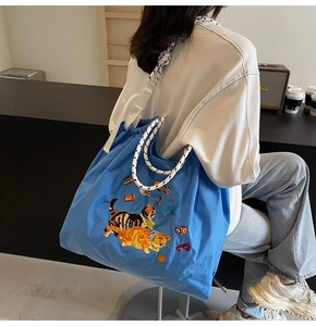 Blaue Canvas-Einkaufstasche mit Katzenstickerei und dicken Seilgriffen in Lifestyle-Umgebung