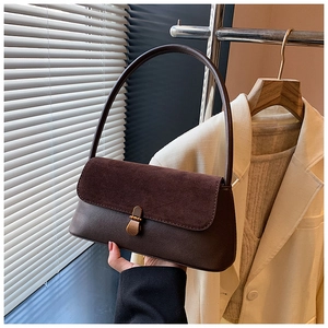 Detail of dark brown faux leather shoulder bag featuring suede flap and metal twist lock