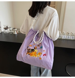Detail der lila Stofftasche mit Katzenstickerei und gepunkteten Kordelgriffen