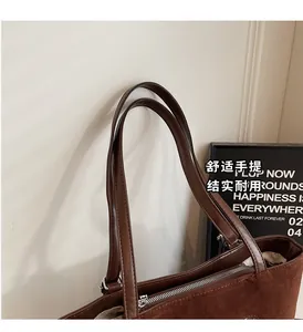 Detailed view of brown suede tote bag featuring leather handles and metal zipper closure