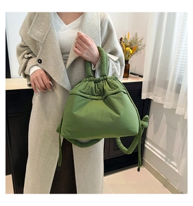 Detail of green quilted tote bag with drawstring closure and padded round handles