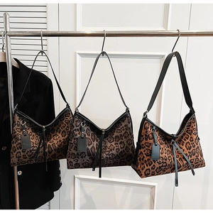 Détail de trois sacs à bandoulière à motif léopard avec des pompons noirs élégants