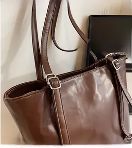 Detail of a brown tote bag with adjustable silver buckle and smooth long shoulder strap