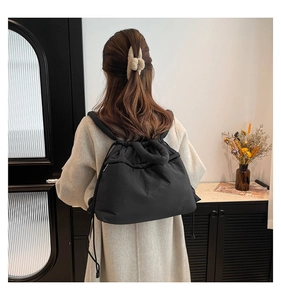Quilted black drawstring backpack shown on model in a minimalist stylish interior
