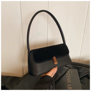 Detail of a vintage black underarm bag showing matte leather and suede texture contrast