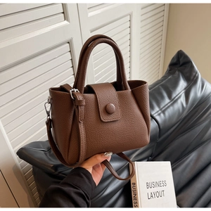 Détail d'un sac à main en cuir marron foncé à texture litchi avec boucle et bandoulière