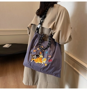 Detail der lila Nylon-Tote mit Katzen-Stickerei und verstellbarem Kordelzug-Gurt