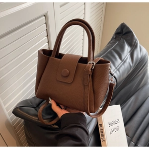 Détail du sac à main marron en cuir grainé avec boucle argentée et bandoulière amovible