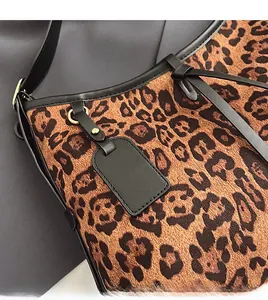 Détail du sac cabas léopard avec étiquette en cuir noir et détails métalliques dorés