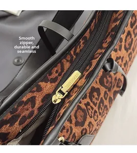 Détail d'une fermeture éclair en métal doré sur un sac léopard avec garniture en cuir noir