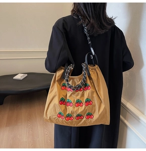 Detailweergave van grote kaki tote bag met kersenborduursel en dikke touwschouderbanden